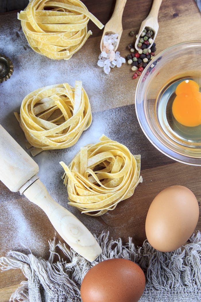 Explore the essentials for homemade pasta with eggs, flour, and pasta next to rustic utensils.
